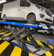 Commercial van undergoing wheel alignment inspection in a vehicle workshop