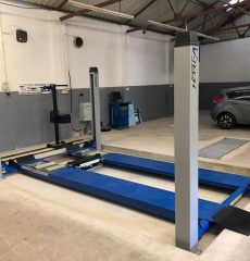Four-post vehicle lift with wheel alignment bay in a professional garage workshop