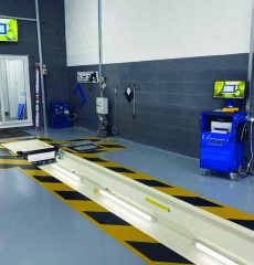 Commercial vehicle inspection pit with wheel alignment equipment in a workshop.