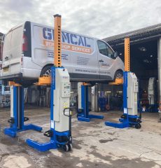 Commercial vehicle raised on mobile column lifts for maintenance.
