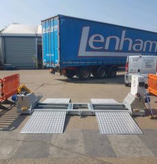 Commercial vehicle positioned on brake testing rollers in a workshop.