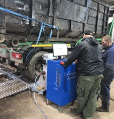 Technician operating vehicle testing equipment in a garage workshop.